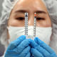 A person holding a low dead space syringe on the left, a normal syringe on the right.